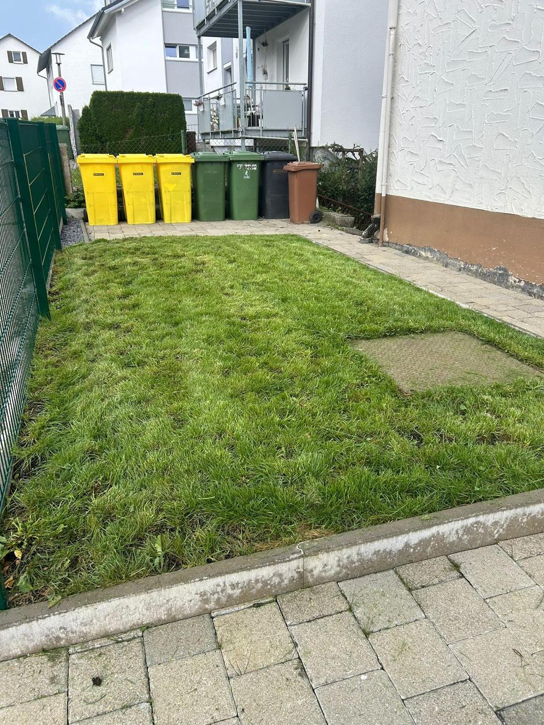Gepflegte Grünfläche und Mülltonnenplatz an einem Wohnhaus